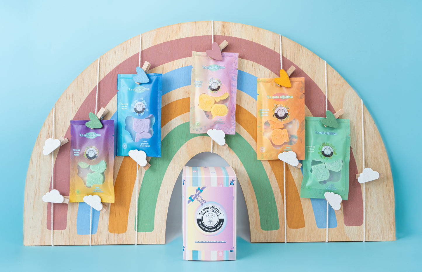 Confezione regalo a tema arcobaleno su sfondo celeste, con colori vivaci e dettagli decorativi allegri che richiamano un’atmosfera gioiosa e giocosa.